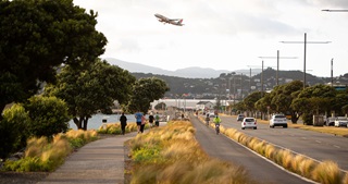 Photograph of a shared street in Wellington with a plane taking off in the distance